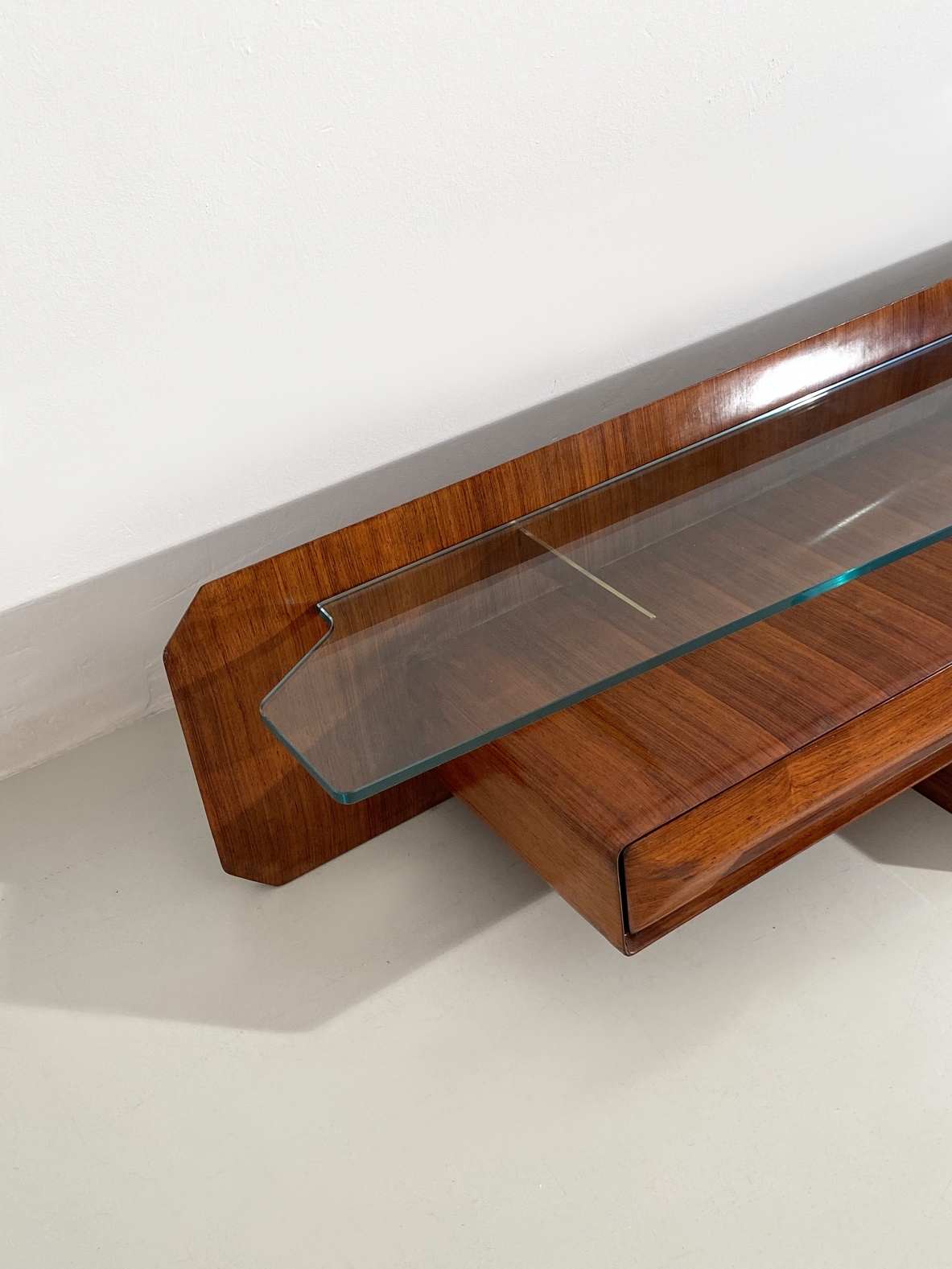 Console pensile in legno di palissandro con cristallo di grande spessore  sagomato sul fronte e su entrambe gli angoli, sospeso su tre bracci in ottone, Italia 1960ca