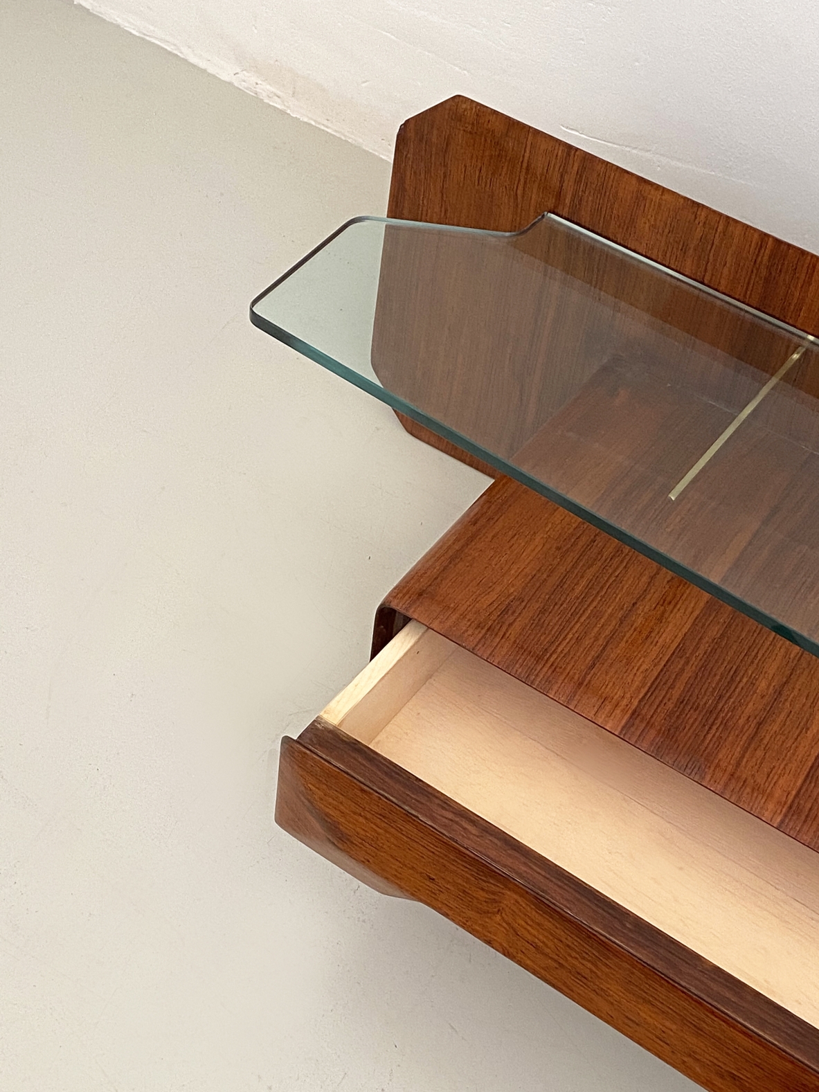 Console pensile in legno di palissandro con cristallo di grande spessore  sagomato sul fronte e su entrambe gli angoli, sospeso su tre bracci in ottone, Italia 1960ca