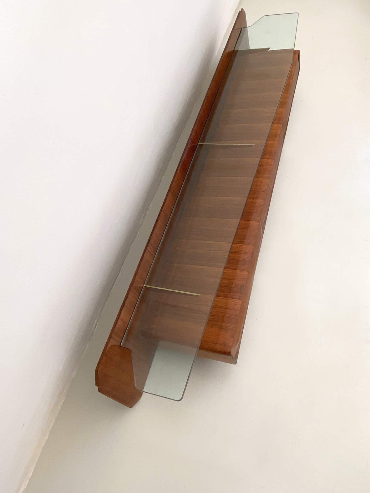 Console pensile in legno di palissandro con cristallo di grande spessore  sagomato sul fronte e su entrambe gli angoli, sospeso su tre bracci in ottone, Italia 1960ca
