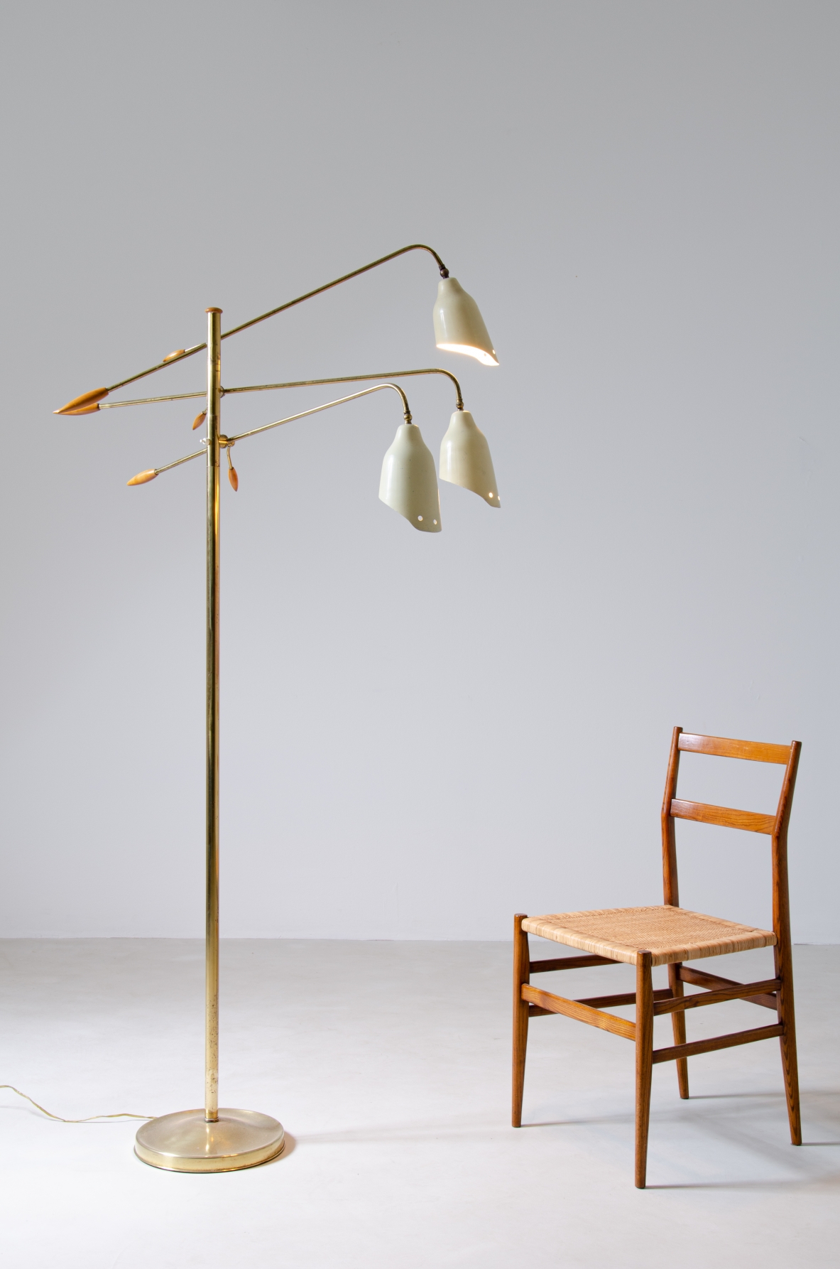 Floor lamp in brass with three adjustable arms and shaped cones in painted metal with elegant ends in turned wood.  Prod. Arredoluce, 1950's.