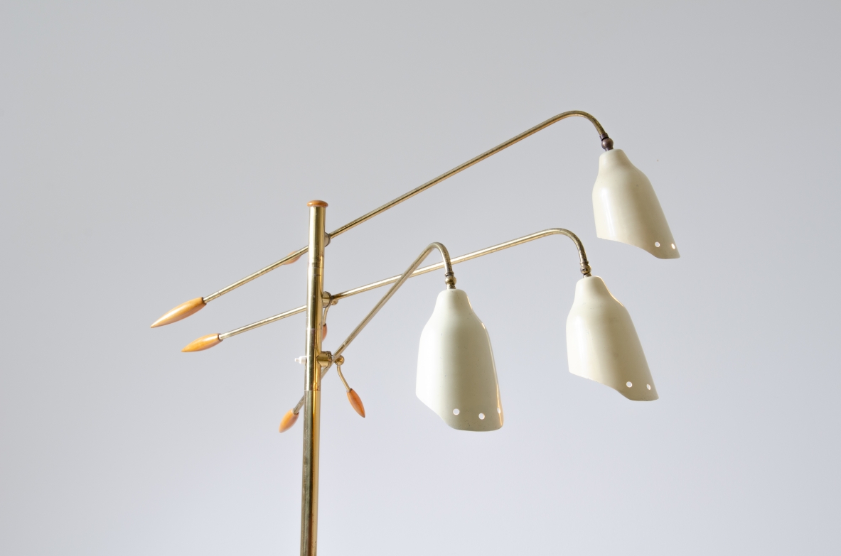 Floor lamp in brass with three adjustable arms and shaped cones in painted metal with elegant ends in turned wood.  Prod. Arredoluce, 1950's.