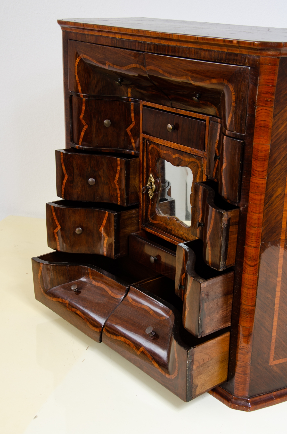 Ebanisteria genovese, 1750ca, monetiere in legno di viola filettato in legno di rosa con fronte mosso, edicola centrale con sportello sagomato e specchio centrale