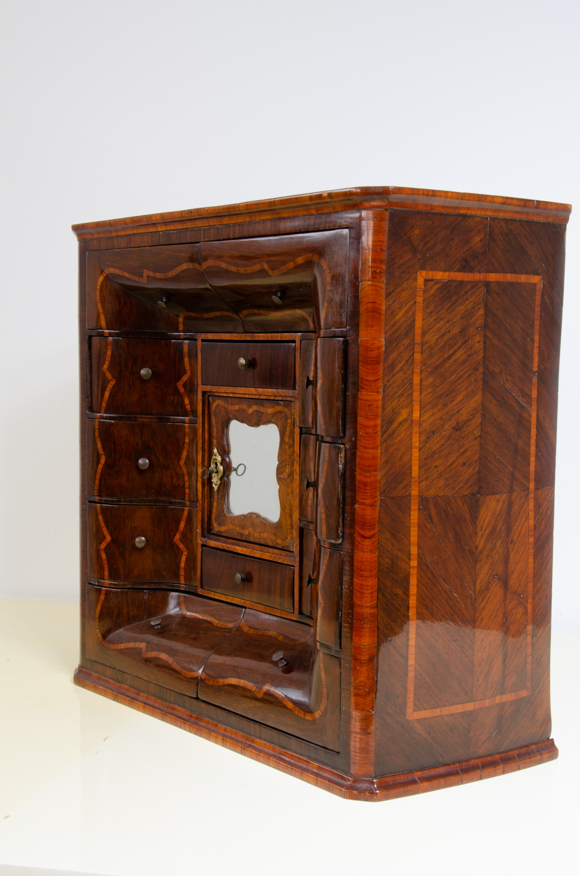 Ebanisteria genovese, 1750ca, monetiere in legno di viola filettato in legno di rosa con fronte mosso, edicola centrale con sportello sagomato e specchio centrale