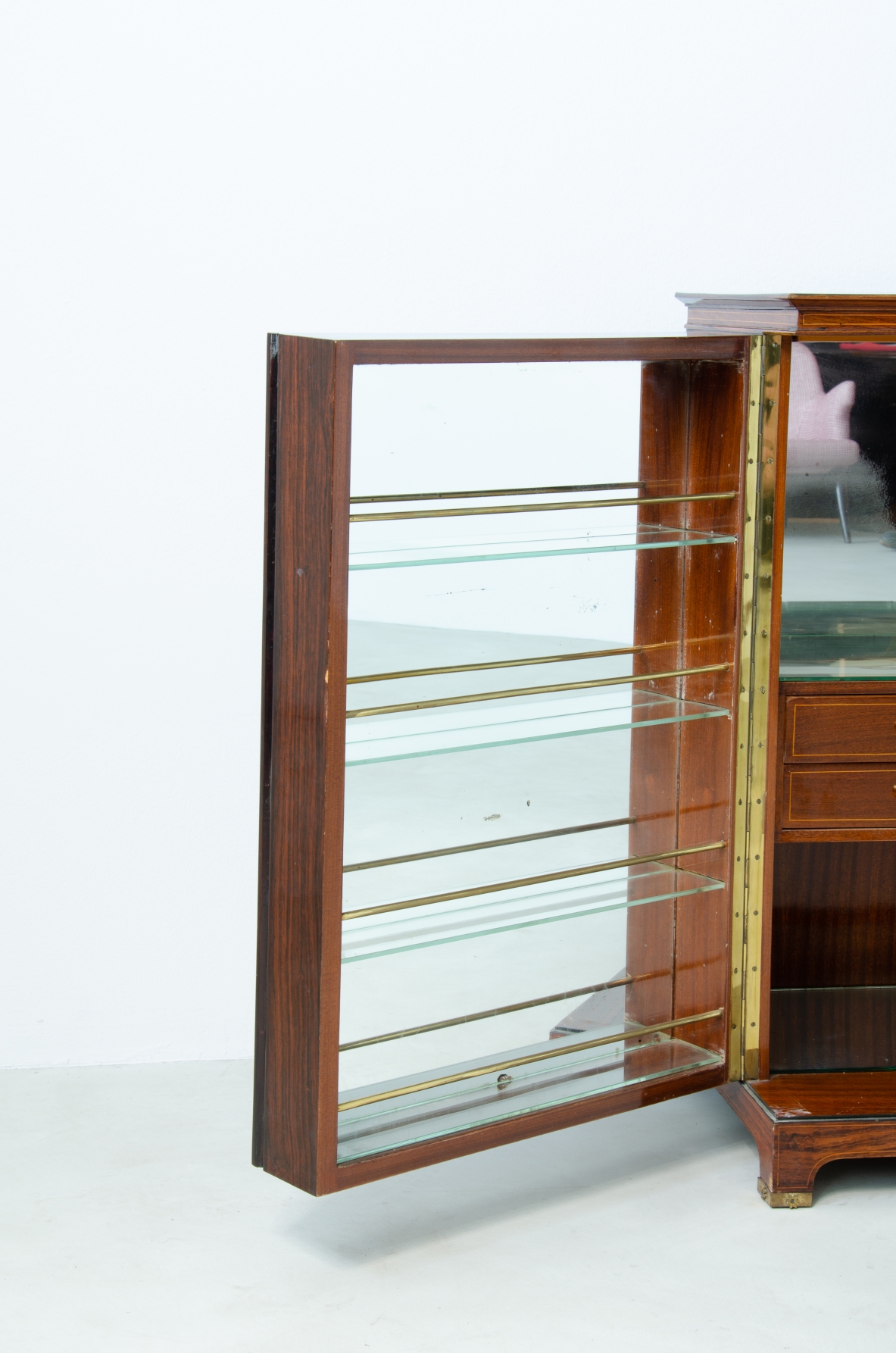Paolo Buffa (1903-1970)  Elegante mobile bar con fronte in palissandro intarsiato e specchiature color ambra. All'interno ripiani e cassetti con scomparti e portabottiglie rivestiti in specchio. Dettagli in ottone.  Manifattura Italiana, 1940ca.