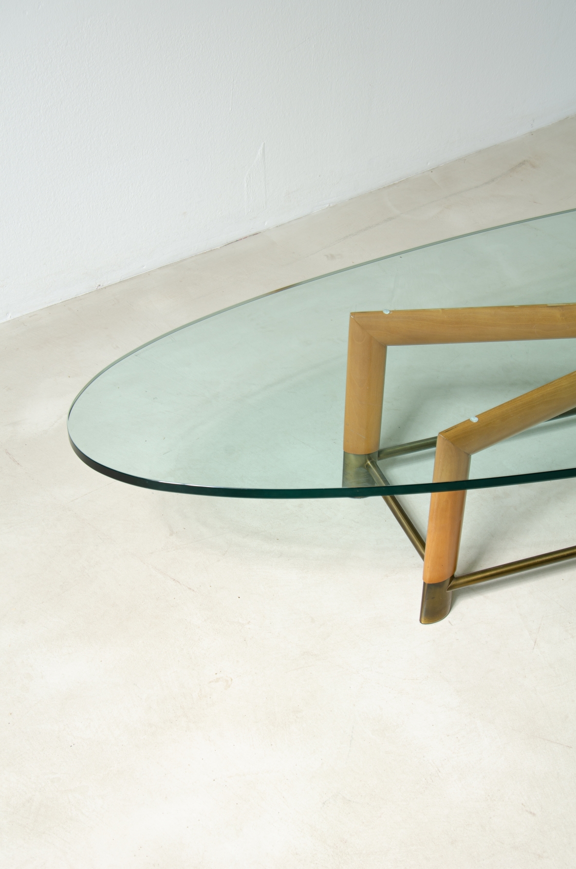 Tavolino ovale con struttura in legno, piedini in ottone e piano in cristallo molato. Manifattura italiana, 1950ca.