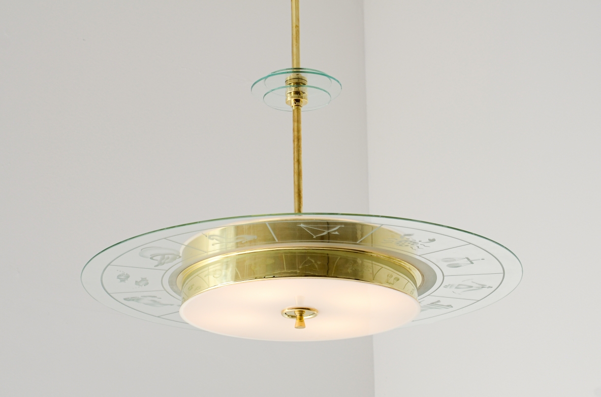 Large brass chandelier with beveled glass decorated with zodiac designs and two milky white glasses. Brass stem with three transparent bevelled glass discs.