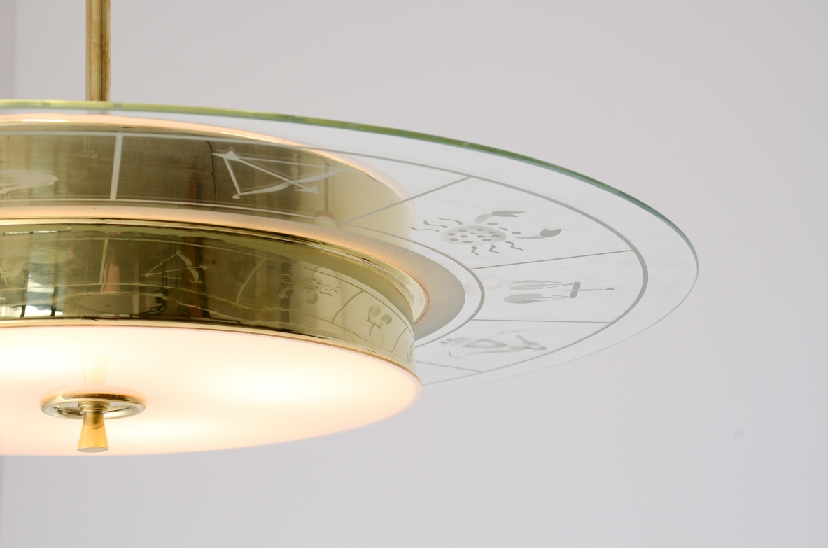 Large brass chandelier with beveled glass decorated with zodiac designs and two milky white glasses. Brass stem with three transparent bevelled glass discs.