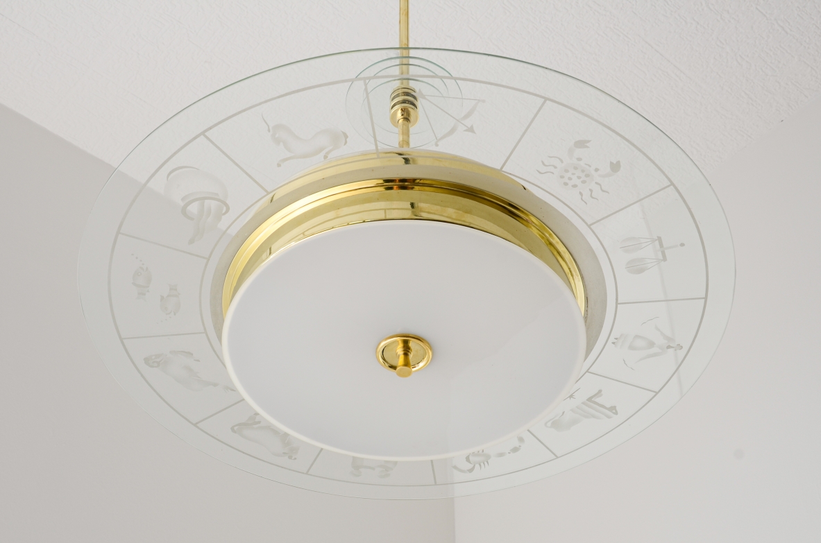 Large brass chandelier with beveled glass decorated with zodiac designs and two milky white glasses. Brass stem with three transparent bevelled glass discs.