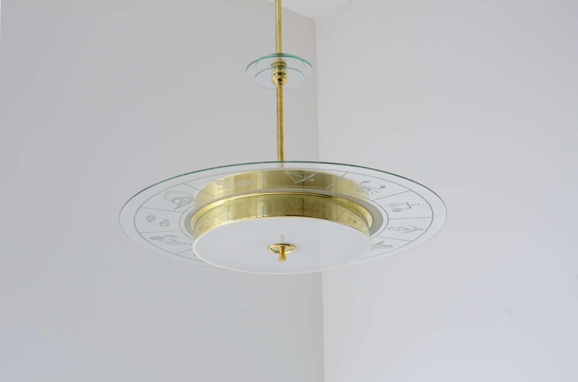 Large brass chandelier with beveled glass decorated with zodiac designs and two milky white glasses. Brass stem with three transparent bevelled glass discs.