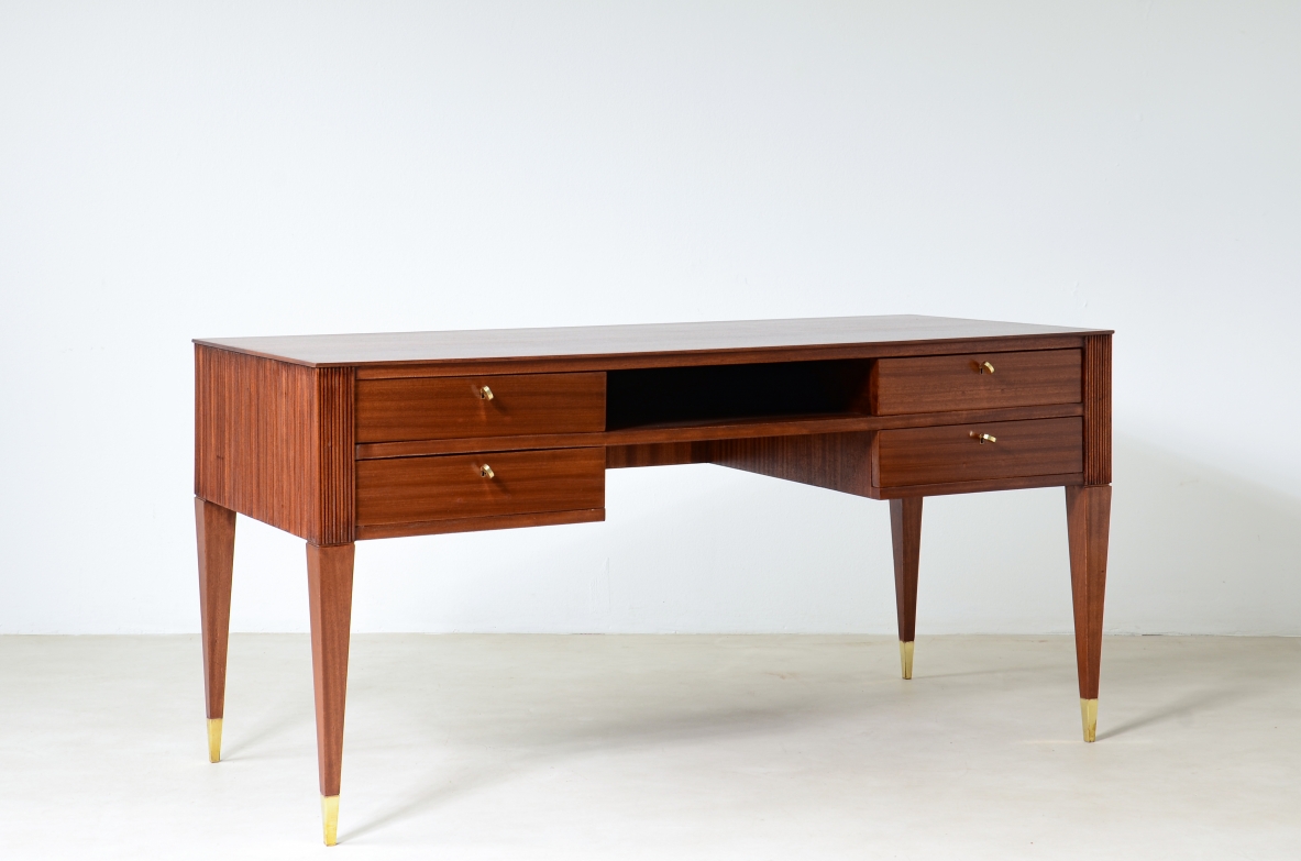 Scrivania in mogano a 4 cassetti con fronte e lati in legno grissinato,      gambe tronco piramidali con puntali in ottone.  Manifattura italiana anni 50'.