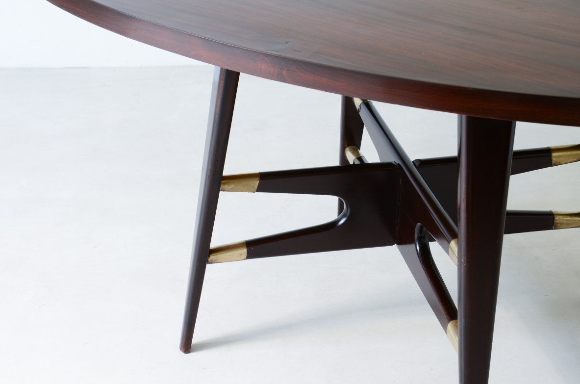Gianni Vigorelli   Elegante tavolo ovale in legno tinto con montanti a quattro gambe e importante crociera con puntali in ottone.  Manifattura italiana, attr. Vigorelli. 1950ca.
