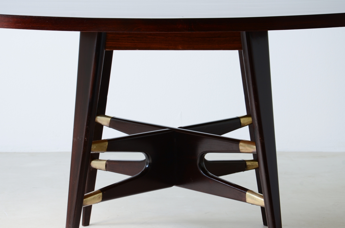 Gianni Vigorelli   Elegante tavolo ovale in legno tinto con montanti a quattro gambe e importante crociera con puntali in ottone.  Manifattura italiana, attr. Vigorelli. 1950ca.