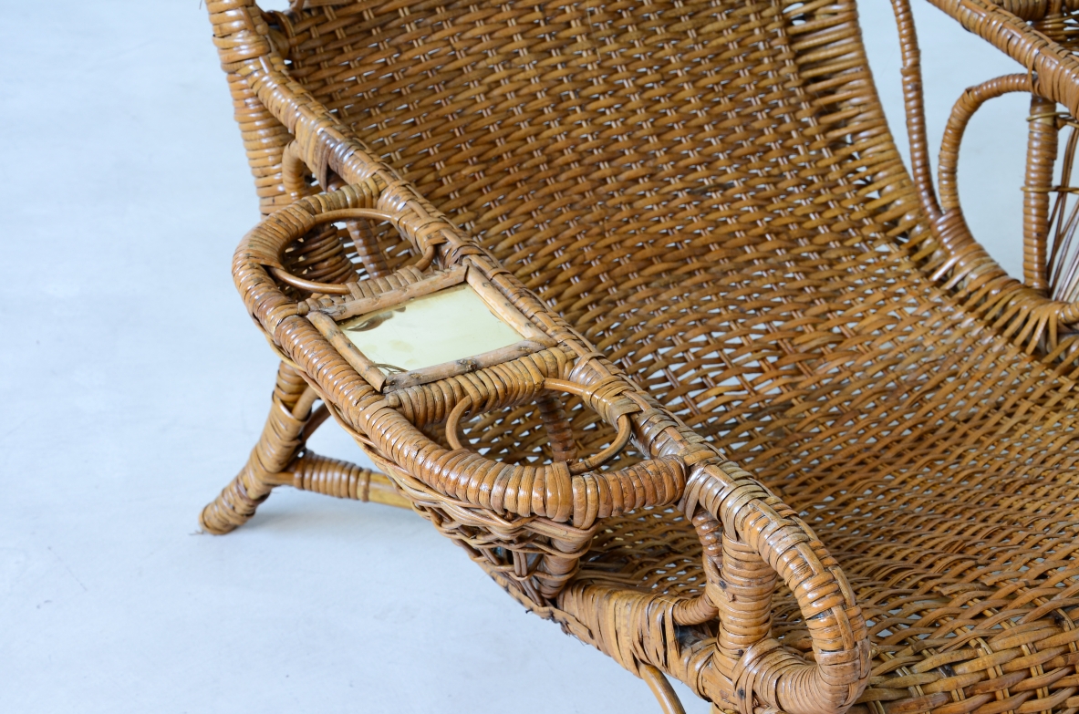 Coppia di raffinate poltrone in raffia e giunco in perfetto stato di conservazione con portariviste, porta bicchiere e appoggio in ottone sui lati.  Manifattura italiana 1930/40ca