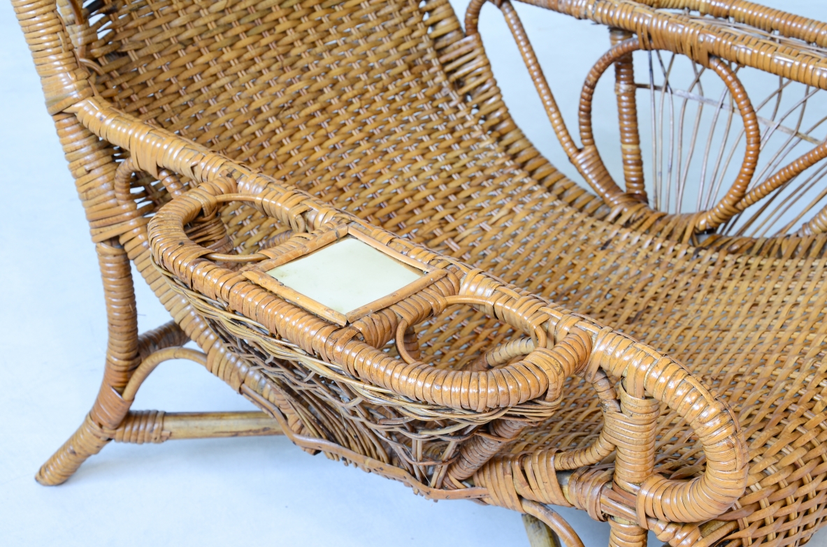 Coppia di raffinate poltrone in raffia e giunco in perfetto stato di conservazione con portariviste, porta bicchiere e appoggio in ottone sui lati.  Manifattura italiana 1930/40ca
