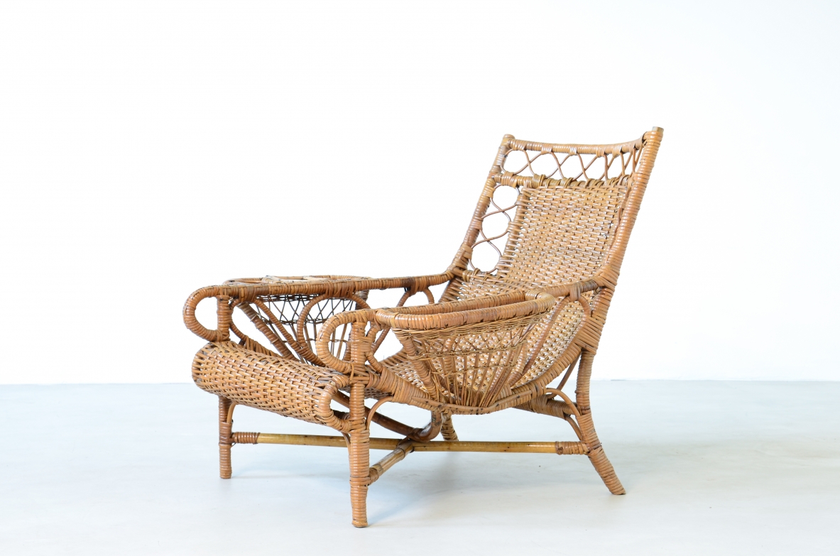 Coppia di raffinate poltrone in raffia e giunco in perfetto stato di conservazione con portariviste, porta bicchiere e appoggio in ottone sui lati.  Manifattura italiana 1930/40ca