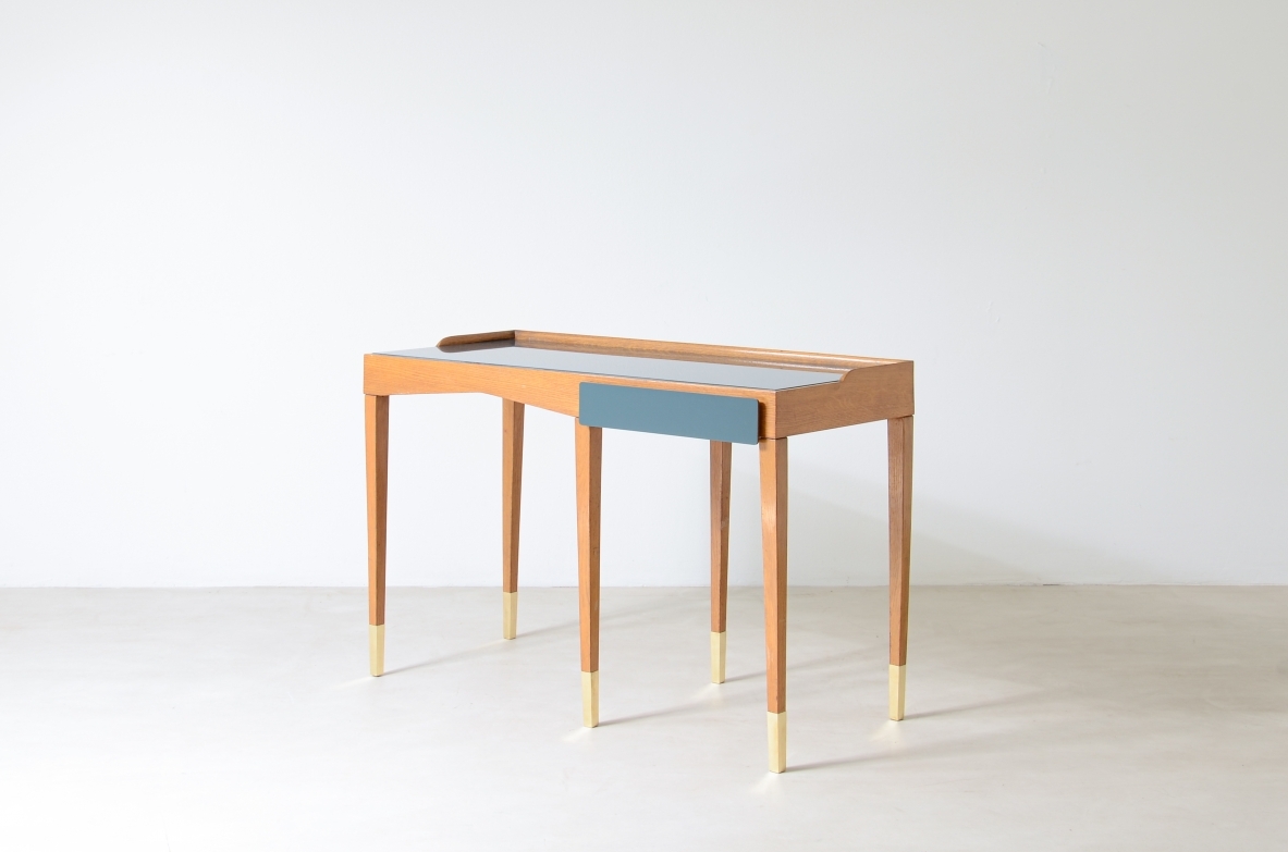 Raffinato scrittoio in rovere con piano in vetro opalino e alzatina e cassetto sagomato rivestito in polipropilene. Lunghe gambe con puntali in ottone.  Attribuzione Gio Ponti, manifattura primi anni 50.