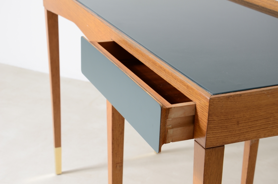 Raffinato scrittoio in rovere con piano in vetro opalino e alzatina e cassetto sagomato rivestito in polipropilene. Lunghe gambe con puntali in ottone.  Attribuzione Gio Ponti, manifattura primi anni 50.