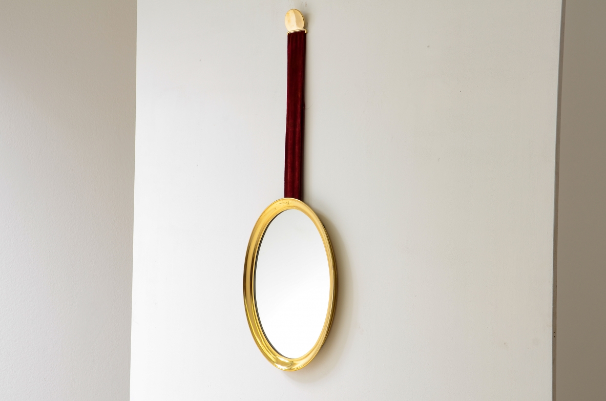 Mirror in shaped brass hanging from an original velvet ribbon and fixed to the wall using a brass disc.  Italian manufacture, 1950s/60s.