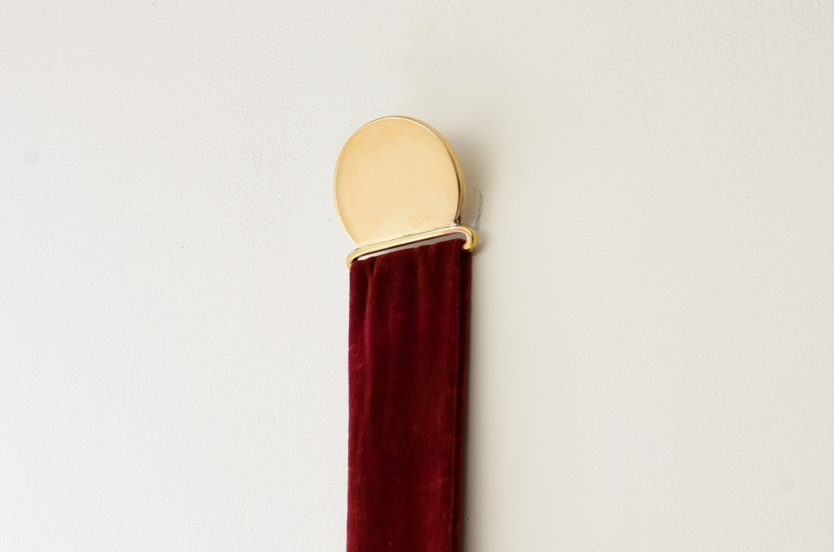 Mirror in shaped brass hanging from an original velvet ribbon and fixed to the wall using a brass disc.  Italian manufacture, 1950s/60s.