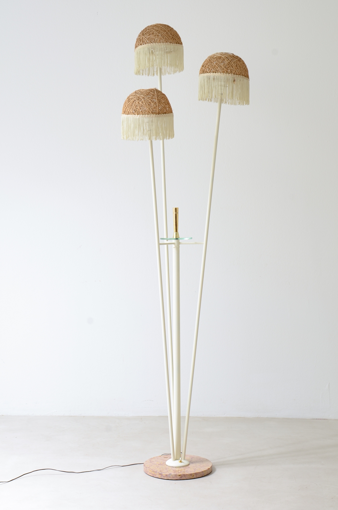 Lampada da terra a tre bracci in metallo laccato con cappelli in rattan e frange in tessuto.Manifattura italiana 1950ca.