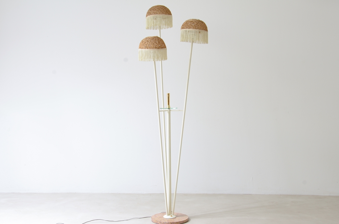 Lampada da terra a tre bracci in metallo laccato con cappelli in rattan e frange in tessuto.Manifattura italiana 1950ca.