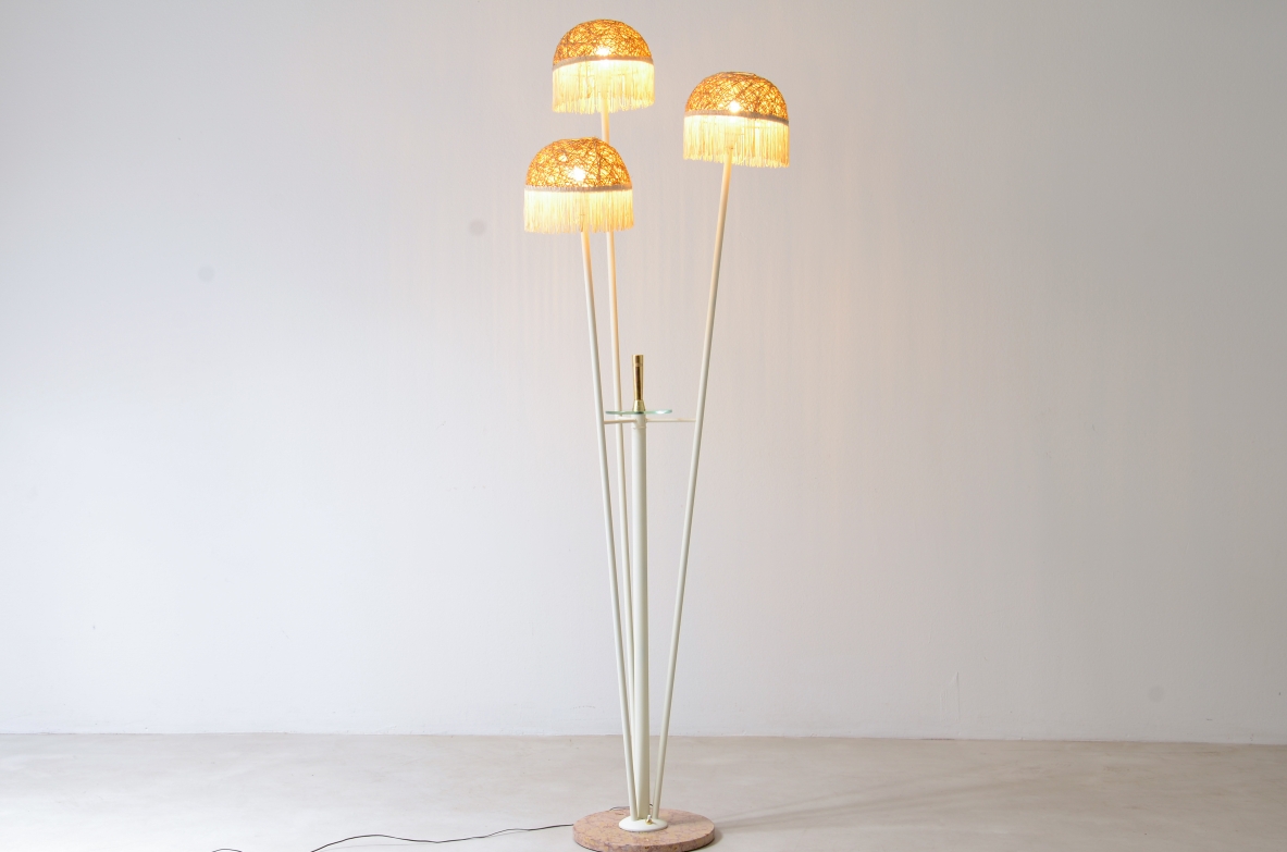 Lampada da terra a tre bracci in metallo laccato con cappelli in rattan e frange in tessuto.Manifattura italiana 1950ca.