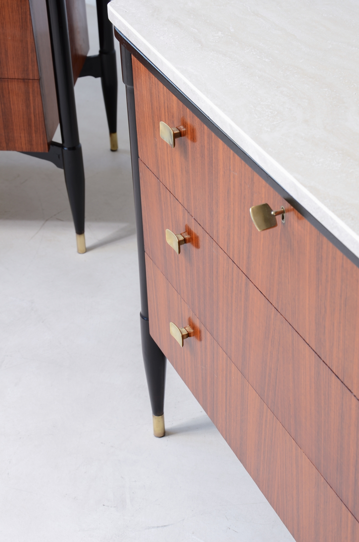 elegant walnut cabinets with travertine tops, three drawers with shaped brass handles. Italian manufacture, circa 1955.