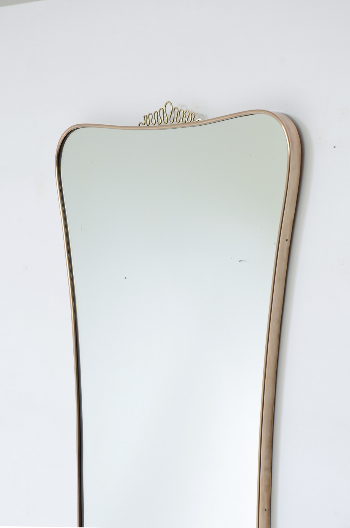 Elegante specchiera con cornice sagomata. Attribuibile a Gio Ponti. Manifattura italiana, anni ’50.