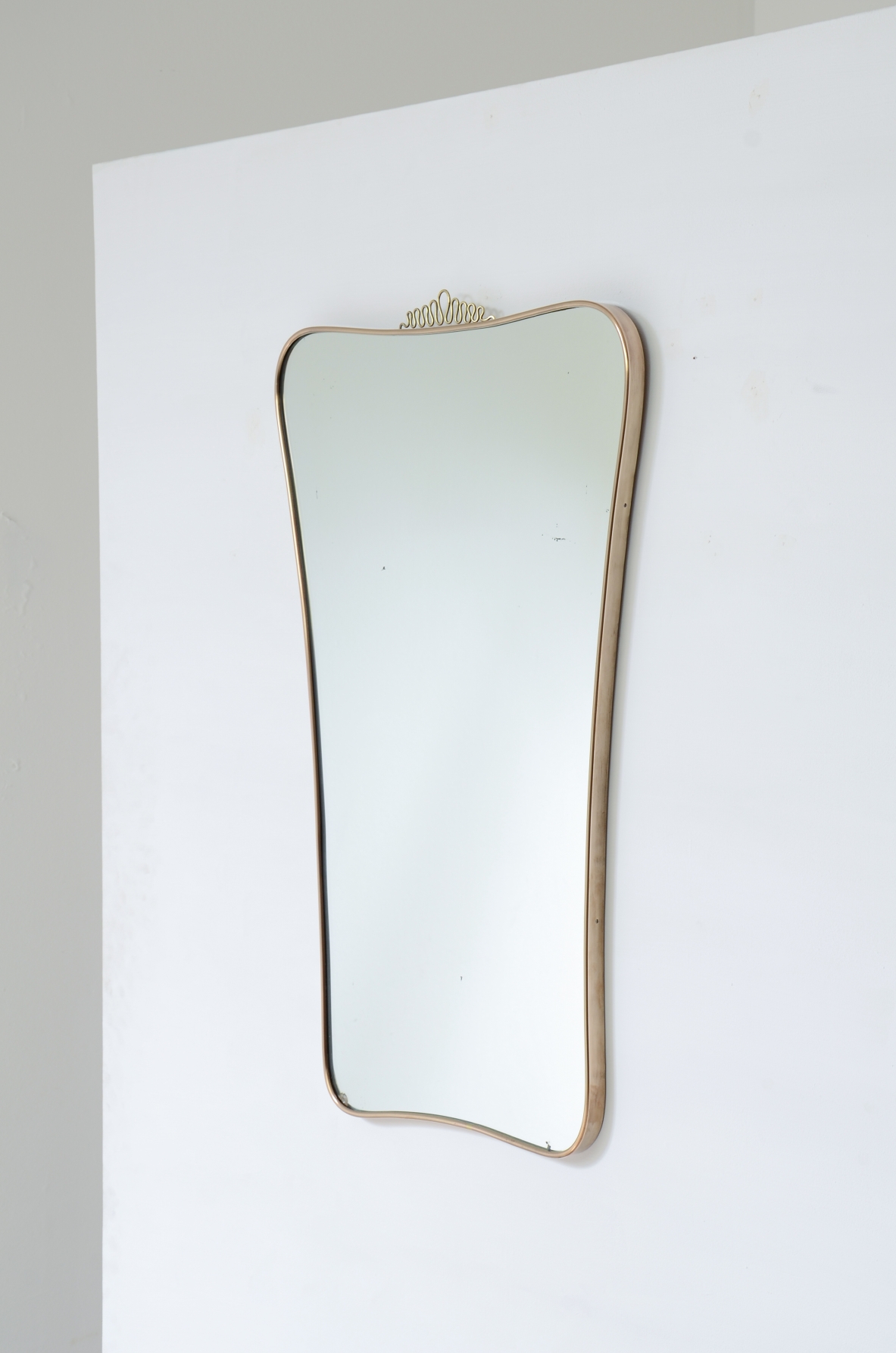 Elegante specchiera con cornice sagomata. Attribuibile a Gio Ponti. Manifattura italiana, anni ’50.