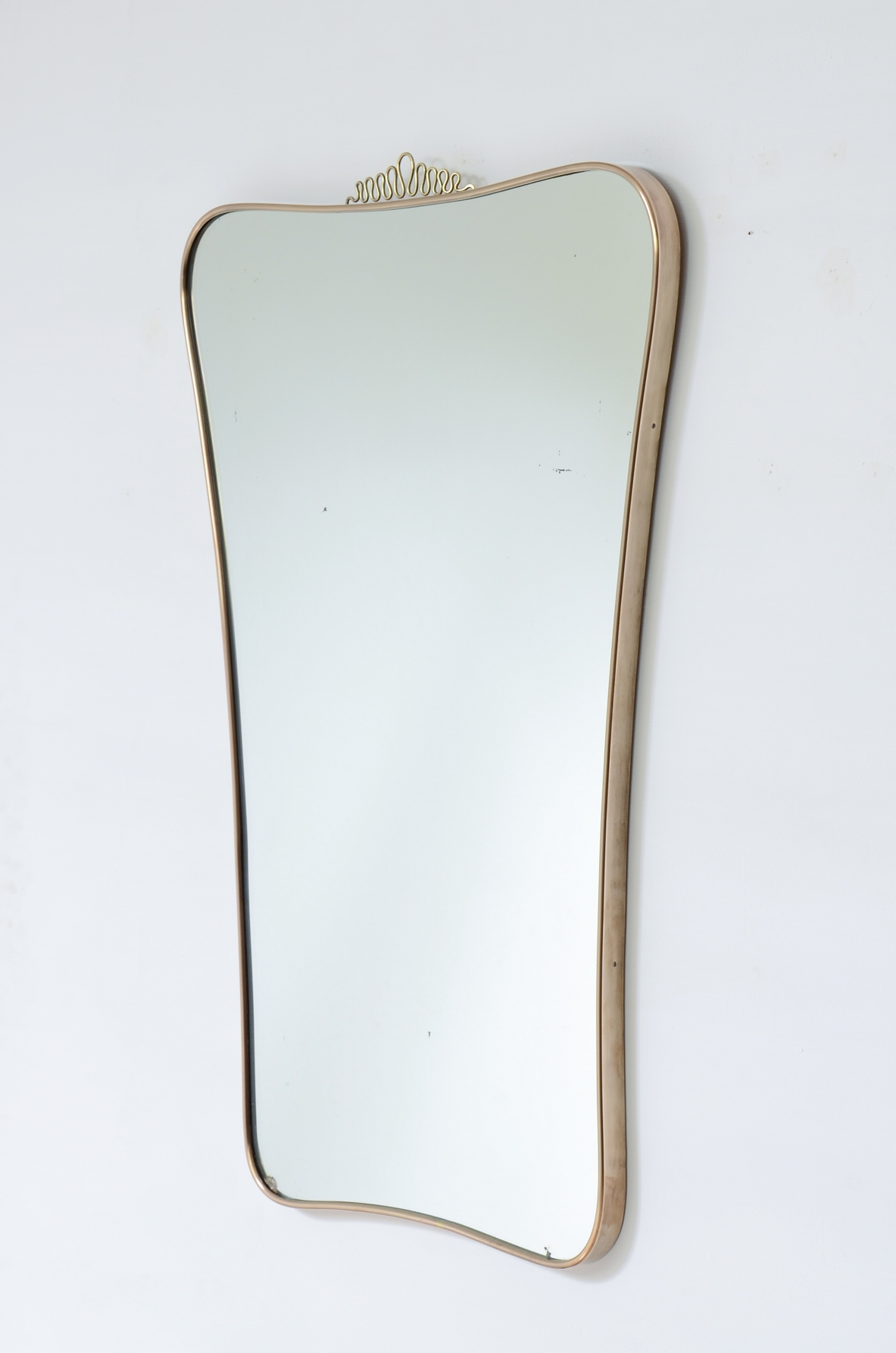Elegante specchiera con cornice sagomata. Attribuibile a Gio Ponti. Manifattura italiana, anni ’50.