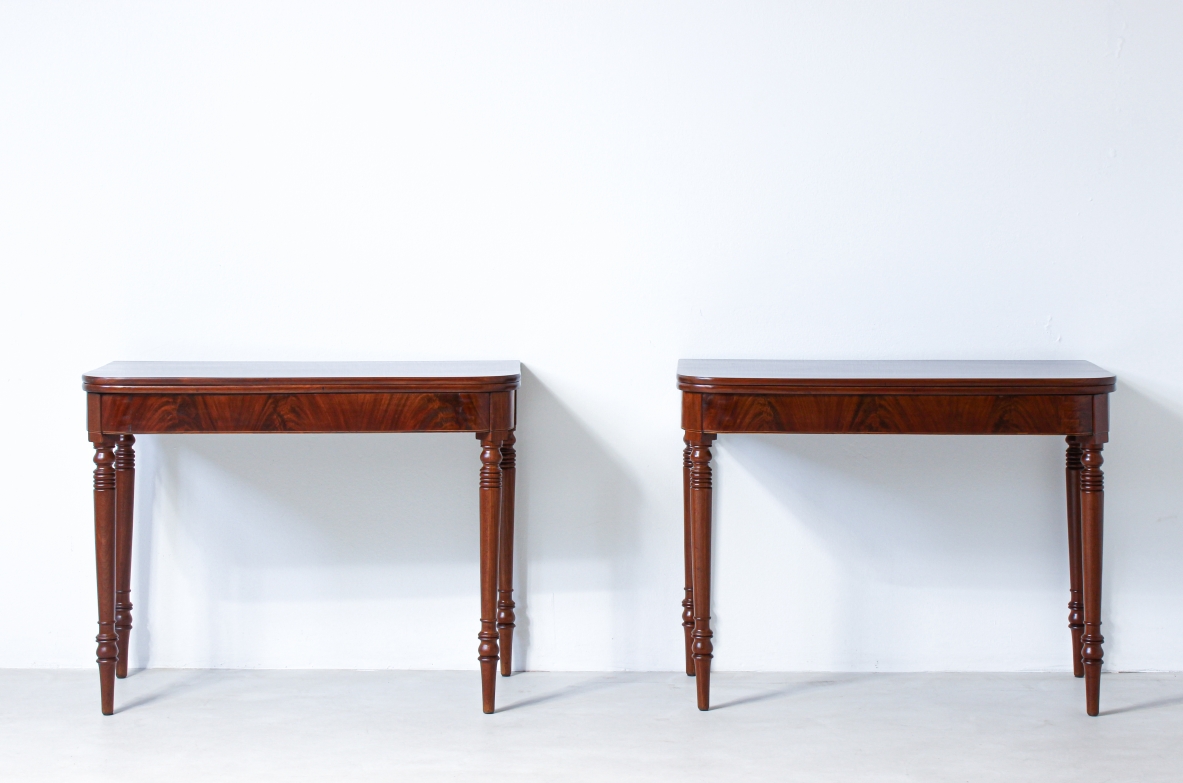 Coppia di eleganti console in mogano con doppio piano a libro e gambe tornite.