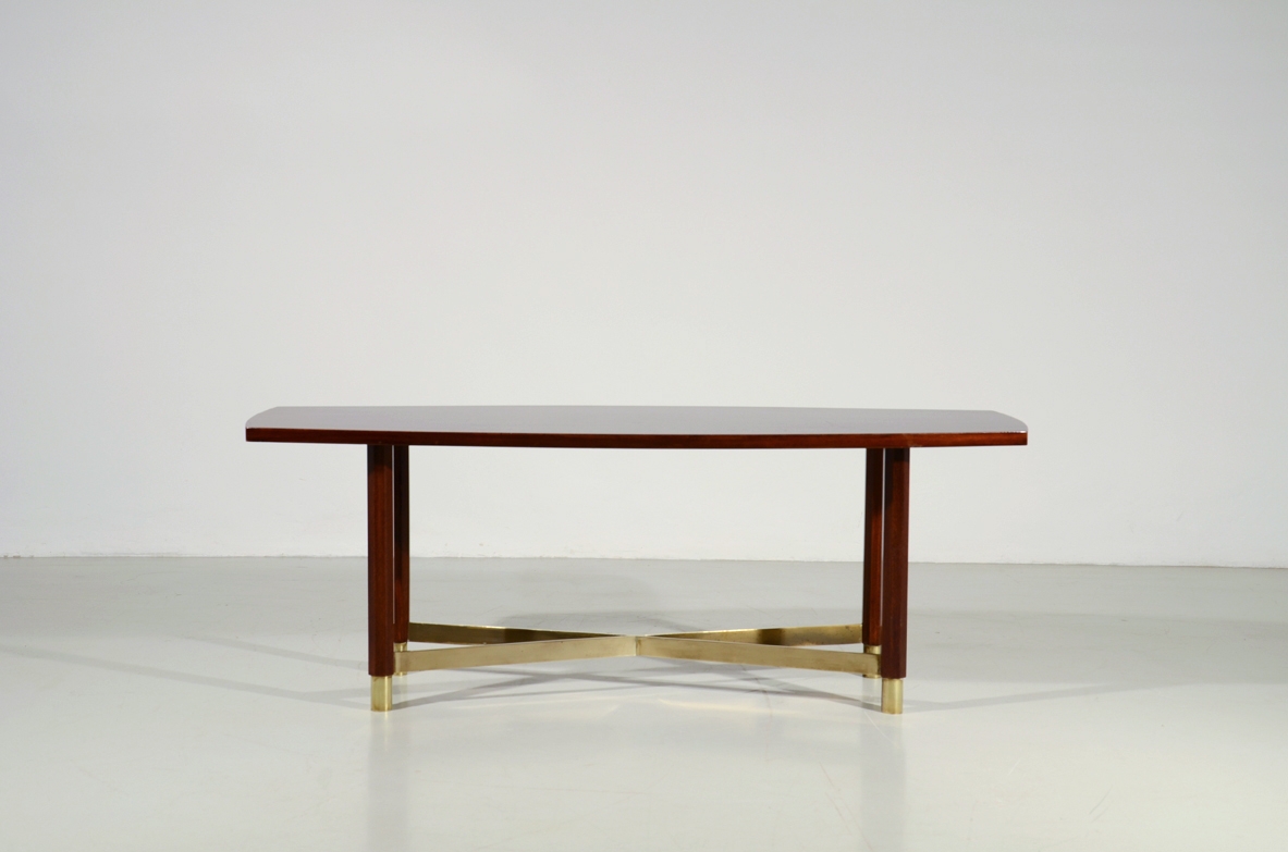 Piccolo elegante tavolino in palissandro con importante crociera alla base e piano leggermente curvato. Manifattura Italiana 1950ca.