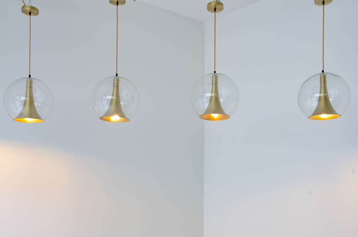 Quattro lampade a sfera in vetro soffiato e coni in ottone.  Manifattura muranese, 1960 ca.