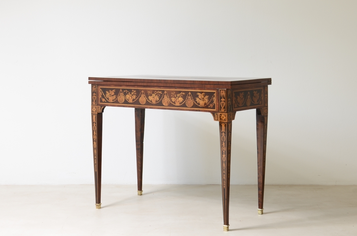 Elegante tavolino da gioco con disegni a intarsio. Interno rivestito in panno.  Manifattura lombarda, epoca Luigi XVI. 1780ca.